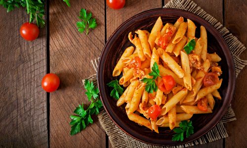 penne-pasta-in-tomato-sauce-with-chicken-and-tomatoes-on-a-wooden-table